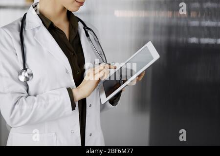 Unbekannter weiblicher Arzt mit Tablet-Computer in der Klinik. Perfekter medizinischer Service im Krankenhaus. Medizinkonzept Stockfoto