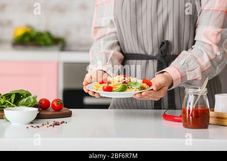 Frau hält Teller mit leckeren Pasta in der Küche, Nahaufnahme Stockfoto