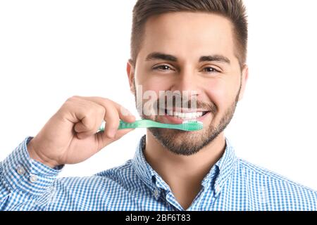 Glücklich lächelnder junger Mann mit Zahnbürste auf weißem Hintergrund Stockfoto