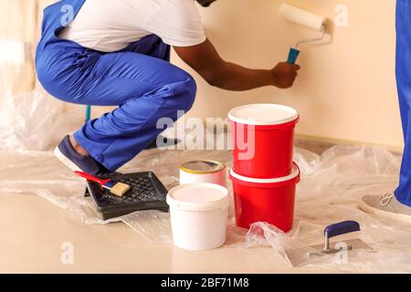 Afroamerikanischer Maler, der im Zimmer Reparatur macht Stockfoto