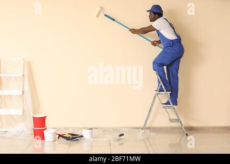 Afroamerikanischer Maler, der im Zimmer Reparatur macht Stockfoto