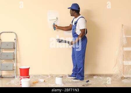 Afroamerikanischer Maler, der im Zimmer Reparatur macht Stockfoto