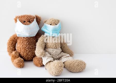 Zwei Teddybären in medizinischen Masken auf weißem Hintergrund. Das Konzept der Selbstisolierung. Bleib zu Hause. Kopierbereich Stockfoto