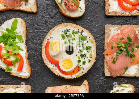 Verschiedene Sandwiches mit leckerem Frischkäse auf dunklem Hintergrund Stockfoto