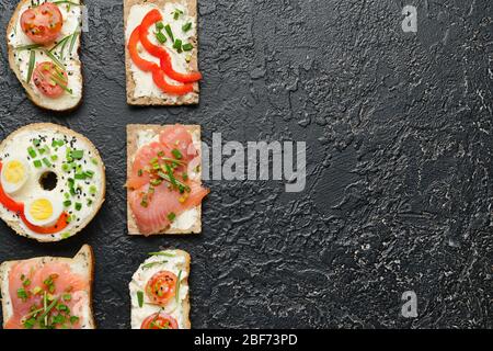 Verschiedene Sandwiches mit leckerem Frischkäse auf dunklem Hintergrund Stockfoto