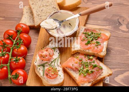 Sandwiches mit leckeren Frischkäse, Lachs und Tomaten auf dem Tisch Stockfoto