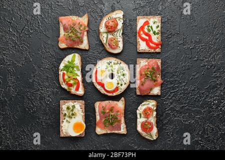 Verschiedene Sandwiches mit leckerem Frischkäse auf dunklem Hintergrund Stockfoto