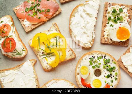Verschiedene Sandwiches mit leckeren Frischkäse auf hellem Hintergrund Stockfoto