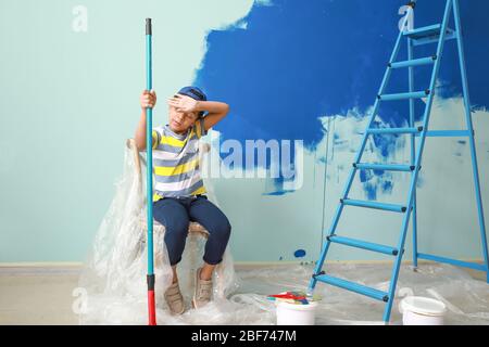 Kleiner afroamerikanischer Junge, der sich nach dem Malen der Wand ausruht Stockfoto