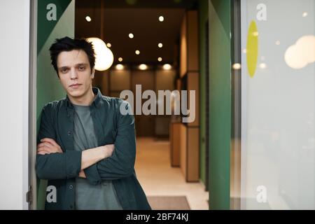 Porträt von schönen jungen Mann in Freizeitkleidung stehen mit gekreuzten Armen und Blick auf die Kamera Stockfoto
