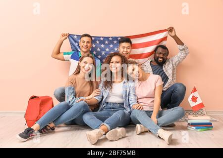 Junge Schüler der Sprachschule sitzen in der Nähe von Farbwand Stockfoto