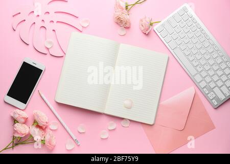 Notebook mit Computer-Tastatur und Handy auf farbigem Hintergrund Stockfoto