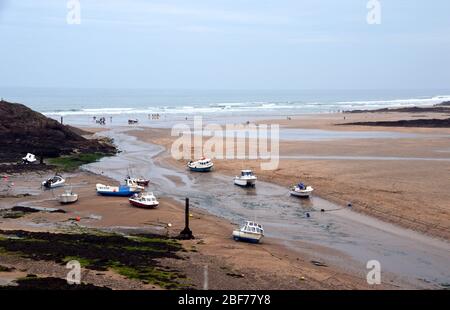 Kleine Fischerboote auf dem Fluss NEET bei Low Tide, wo es das Meer trifft auf Bude Beach auf dem South West Coast Path, North Cornwall, England. Stockfoto