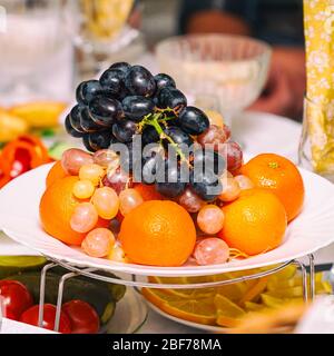 Obsttrauben, Orangen, Tangerinen, Zitrone auf dem Ferientisch Stockfoto