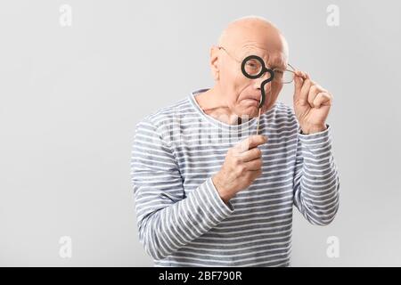 Portrait des älteren Mannes mit Party-Dekor auf grauem Hintergrund Stockfoto