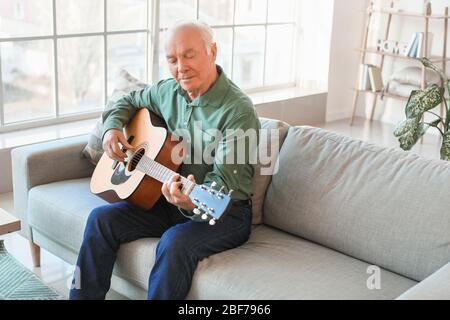 Älterer Mann, der zu Hause Gitarre spielt Stockfoto