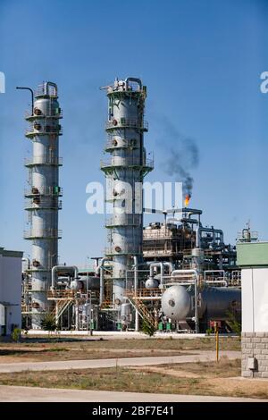 Petrochemische Anlage. Ölraffinerie-Anlage. Destillationstürme, Pipelines und brennende Gasbrenner auf blauem Himmel Hintergrund. Stockfoto