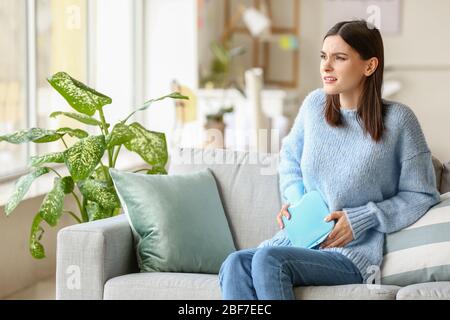 Junge Frau, die zu Hause an Menstruationskrämpfen leidet Stockfoto