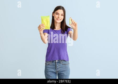 Junge Frau mit Pad und Menstruationstampon auf hellem Hintergrund Stockfoto