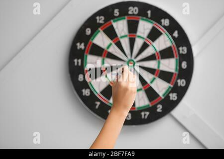 Junge Frau, die Darts in Innenräumen spielt Stockfoto