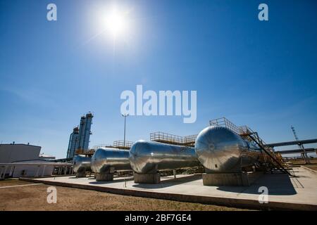 Ölraffinerie und Gasverarbeitungsanlage in der Wüste. Ein paar Wärmetauscher und Destillationstürme (Raffineriesäulen) auf blauem Himmel mit Sonne. Stockfoto