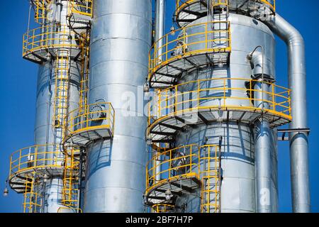 Nahaufnahme der grauen Metallölraffiniersäulen (Destillationstürme) am blauen Himmel. Ölraffinerie und Gasverarbeitungsanlage. Stockfoto