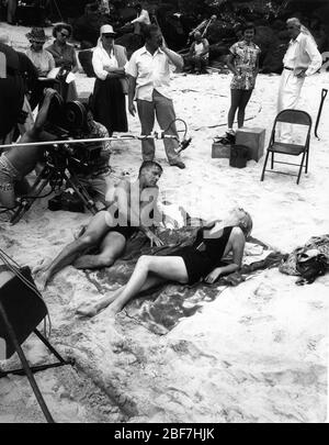 BURT LANCASTER und DEBORAH KERR mit Movie Crew und Produzent BUDDY Adler (oben rechts) am Set-Ort Candid in Halona Cove, O'ahu Hawaii filmt die berühmte Strandliebszene für FROM HERE TO ETERNITY 1953 Regisseur FRED ZINNEMANN Roman James Jones Drehbuch Daniel Taradash Columbia Pictures Stockfoto
