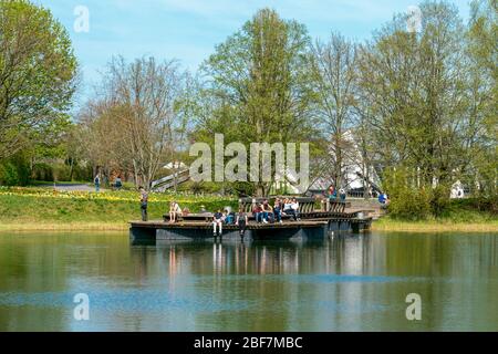 Britzer Garten, Berlin, Deutschland - 16. april 2020: Besucher genießen die Sonne auf dem Seeplattform Stockfoto