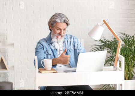 Emotional älterer Mann mit Laptop im Büro Stockfoto