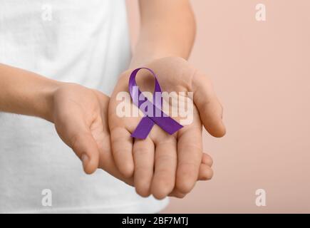 Frau mit violettem Band auf farbigem Hintergrund, Nahaufnahme. Konzept der häuslichen Gewalt Stockfoto