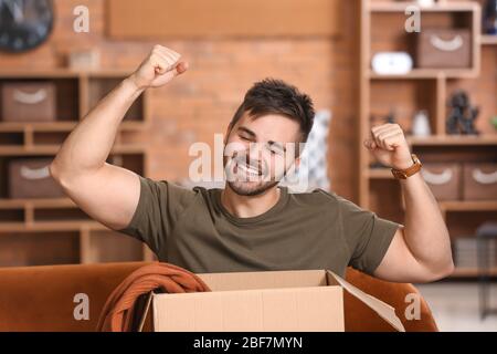Happy man Auspacken Box mit neuen Kleidern zu Hause Stockfoto