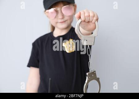 Niedliche kleine Polizist mit Handschellen auf hellem Hintergrund Stockfoto