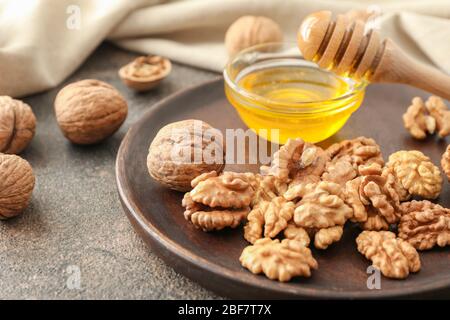 Schüssel mit Honig und leckeren Walnüssen auf dem Tisch Stockfoto