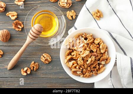 Schüssel mit leckeren Walnüssen und Honig auf dem Tisch Stockfoto