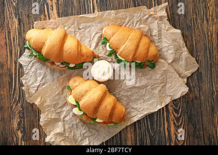 Leckere Croissant-Sandwiches mit Sauce auf Holztisch Stockfoto