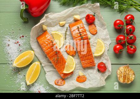 Papier mit gekochtem Lachsfilet und Gemüse auf dem Tisch Stockfoto