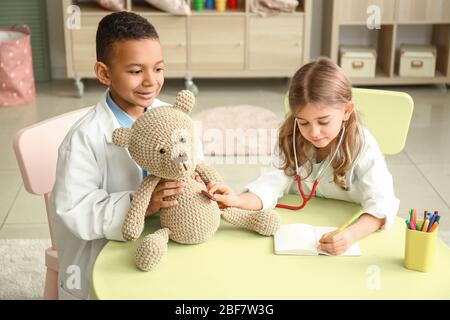 Süße kleine Kinder, die als Ärzte verkleidet sind und zu Hause spielen Stockfoto