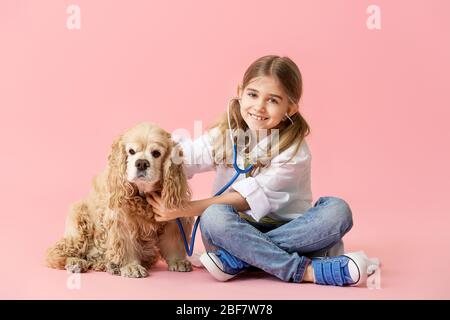 Nette kleine Tierarzt mit Hund auf farbigen Hintergrund Stockfoto