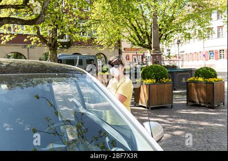 Sulz Am Neckar, Deutschland. April 2020. Eine Frau geht mit einem Mundschutz zu ihrem Auto auf dem Marktplatz. Aufgrund der erhöhten Koronazahlen in Sulz am Neckar (Landkreis Rottweil) sind dort seit 17.04.2020 Masken vorgeschrieben. Kredit: Silas Stein/dpa/Alamy Live News Stockfoto