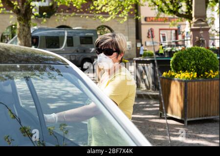 Sulz Am Neckar, Deutschland. April 2020. Eine Frau geht mit einem Mundschutz zu ihrem Auto auf dem Marktplatz. Aufgrund der erhöhten Koronazahlen in Sulz am Neckar (Landkreis Rottweil) sind dort seit 17.04.2020 Masken vorgeschrieben. Kredit: Silas Stein/dpa/Alamy Live News Stockfoto