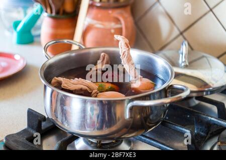 Traditionelle Art der ostereifärbung. Kleine Pflanzenblätter mit Strümpfen auf Eier gepresst, in kochendes Wasser mit roter Zwiebel geben. Schritt 2 von 3. Stockfoto