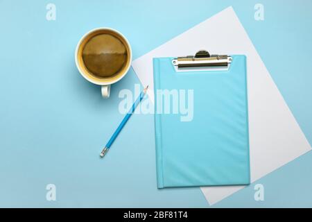 Clipboard, Papier, Bleistift und Tasse Kaffee auf farbigen Hintergrund Stockfoto