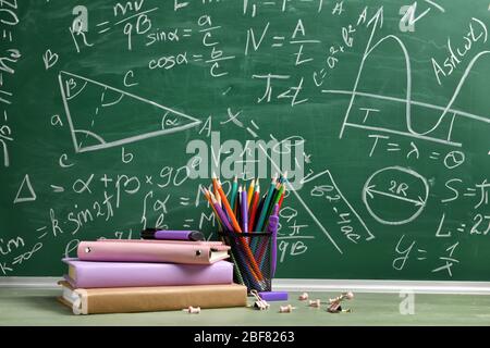 Set von Schulbedarf auf dem Tisch neben Tafel Stockfoto