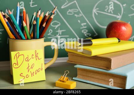 Set von Schulbedarf und Apfel auf dem Tisch in der Nähe Tafel Stockfoto