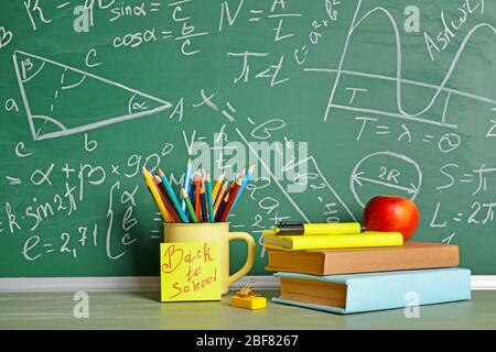 Set von Schulbedarf und Apfel auf dem Tisch in der Nähe Tafel Stockfoto