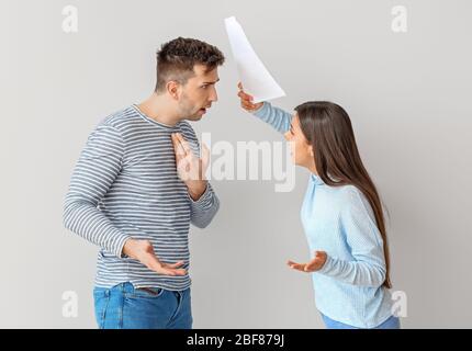 Missfiel Frau schimpft ihren Mann für zu viel Geld auf hellen Hintergrund Stockfoto