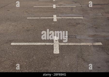 Alte, schmutzige und verblassende weiße Markierungen auf einem leeren Parkplatz Stockfoto