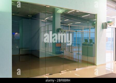 Leeres Zimmer oder Geschäft hinter Glasfenster und Türen im öffentlichen Raum. Stockfoto