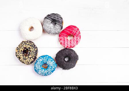Bunt dekorierte Donuts auf weißem Holzhintergrund. Süße Donuts auf dem Tisch. Stockfoto
