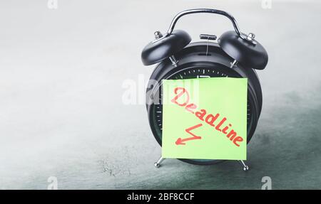 Wecker und Papier mit TEXTSCHLUSS auf dem Tisch Stockfoto